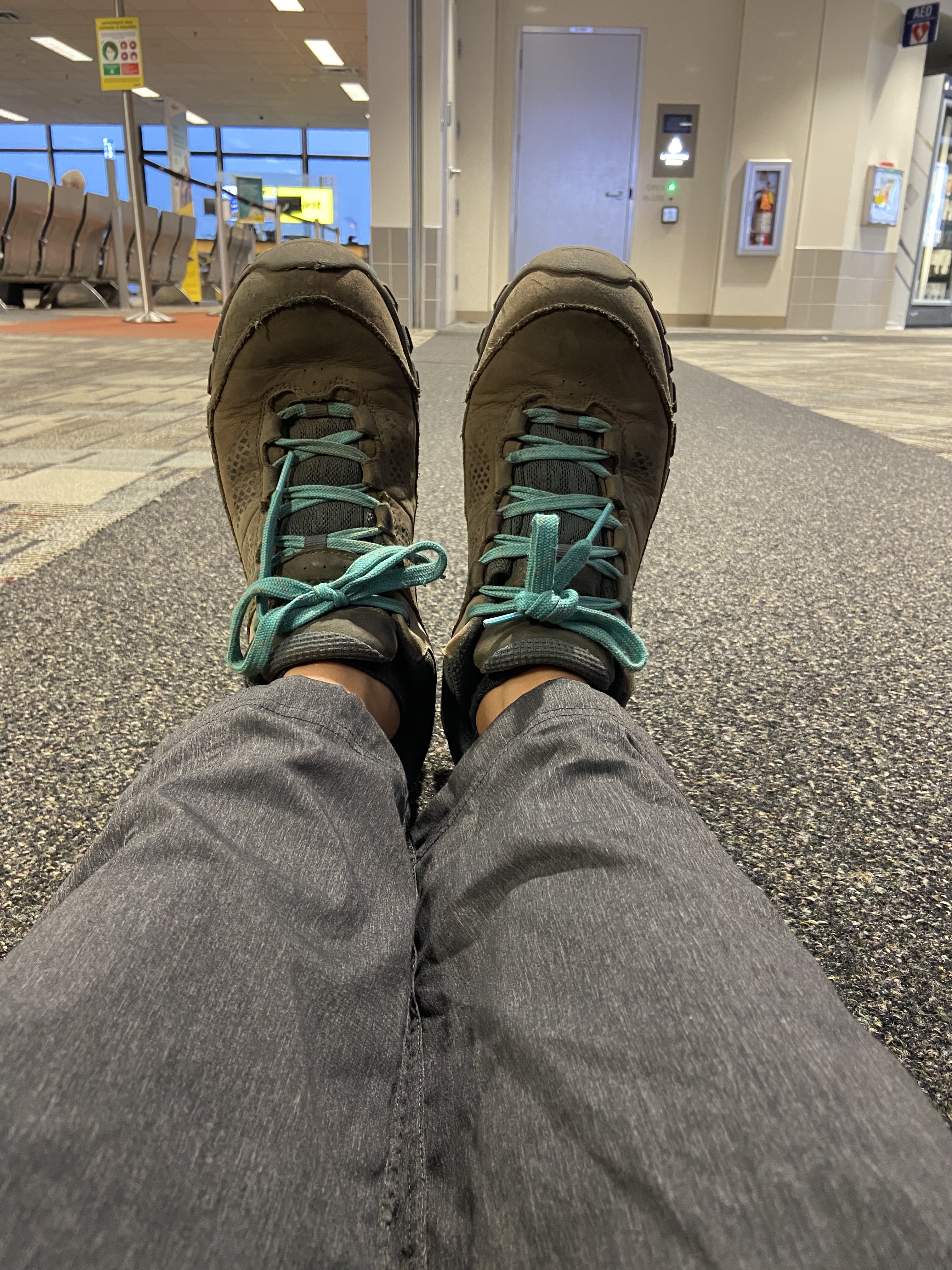 A picture of feet wearing hiking shoes in an airport.