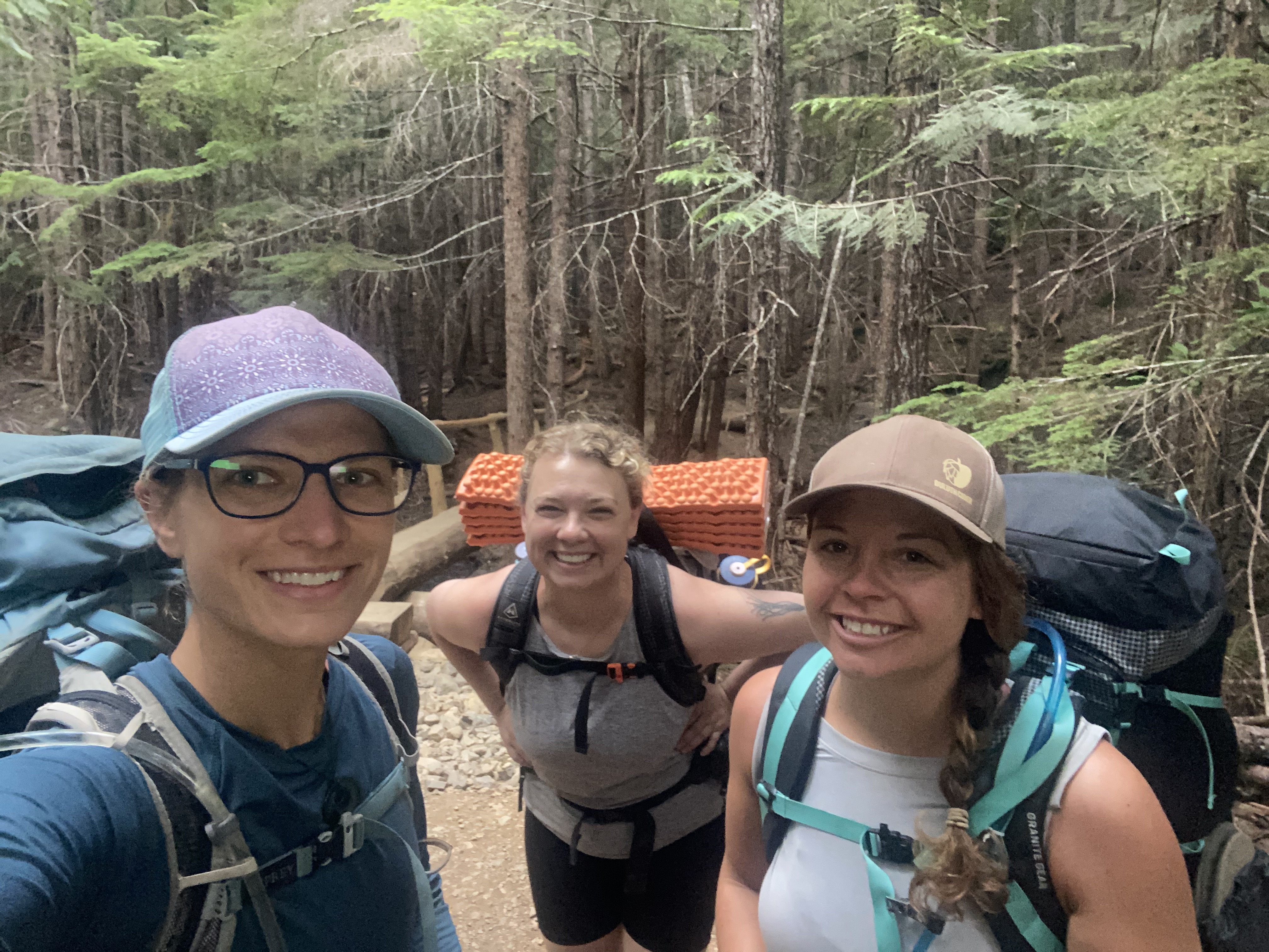 Three women wearing backpacks.