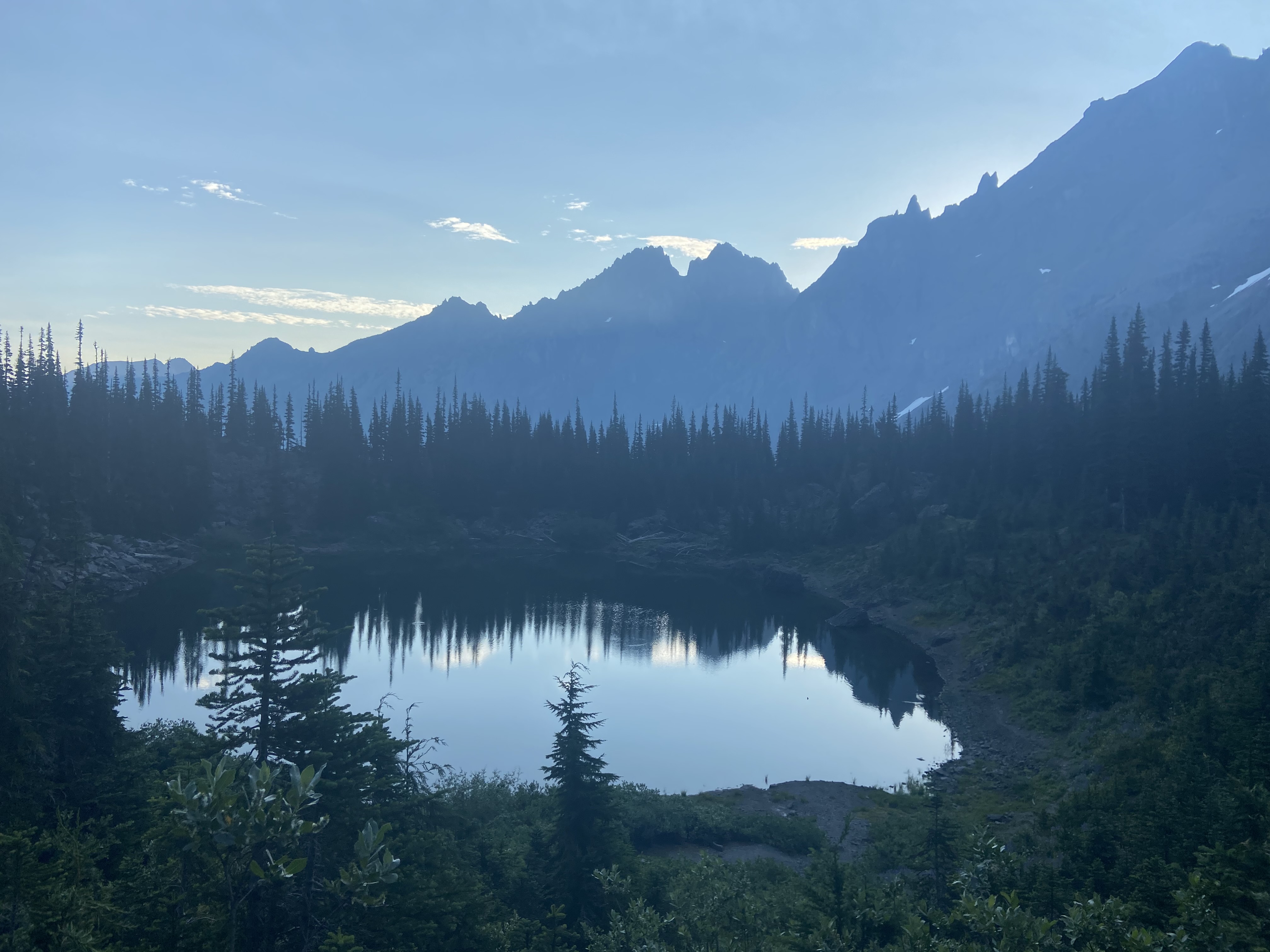 An alpine lake in the early morning with peaks in the background.