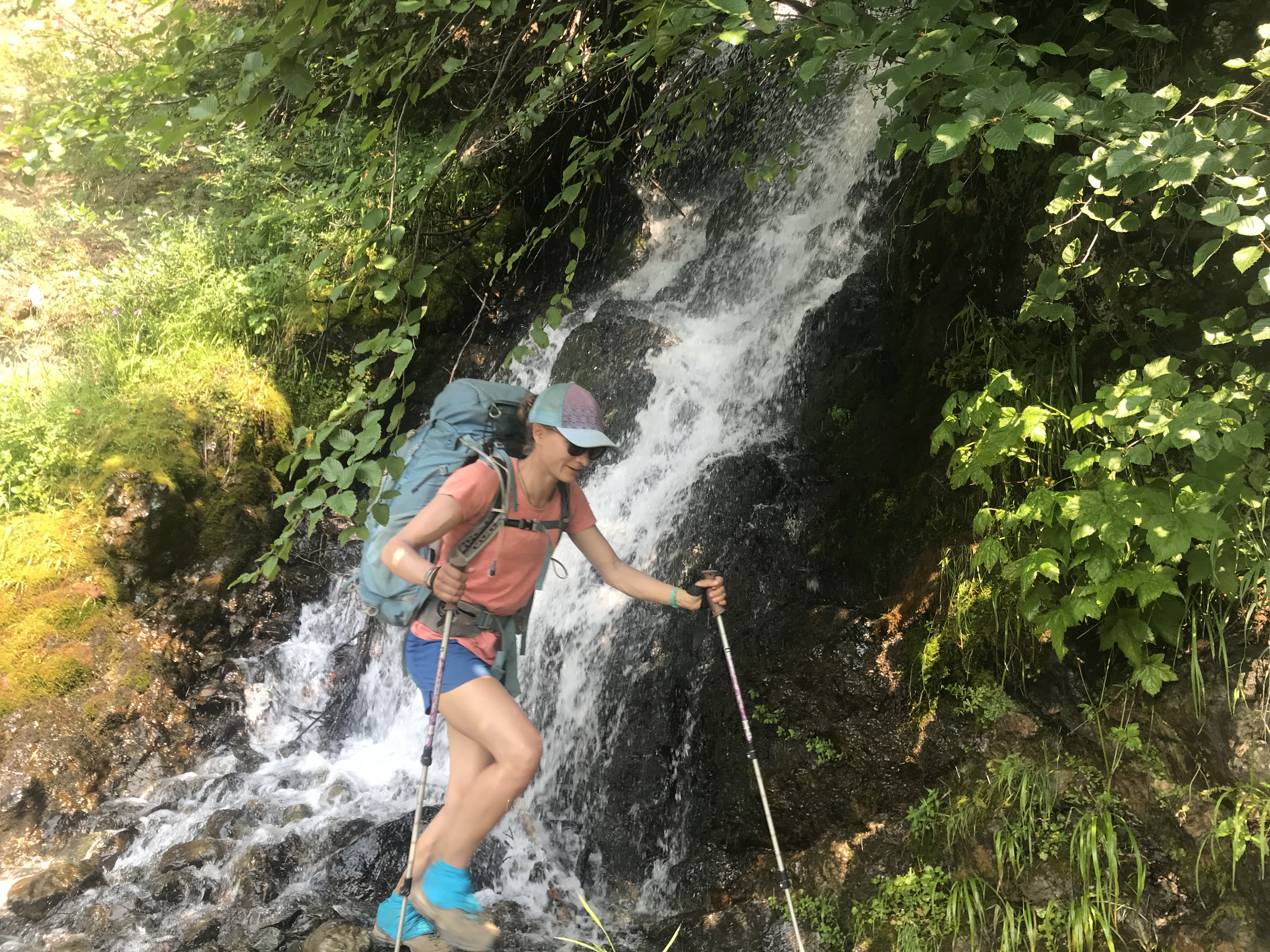 A woman hiking with a waterfall behind