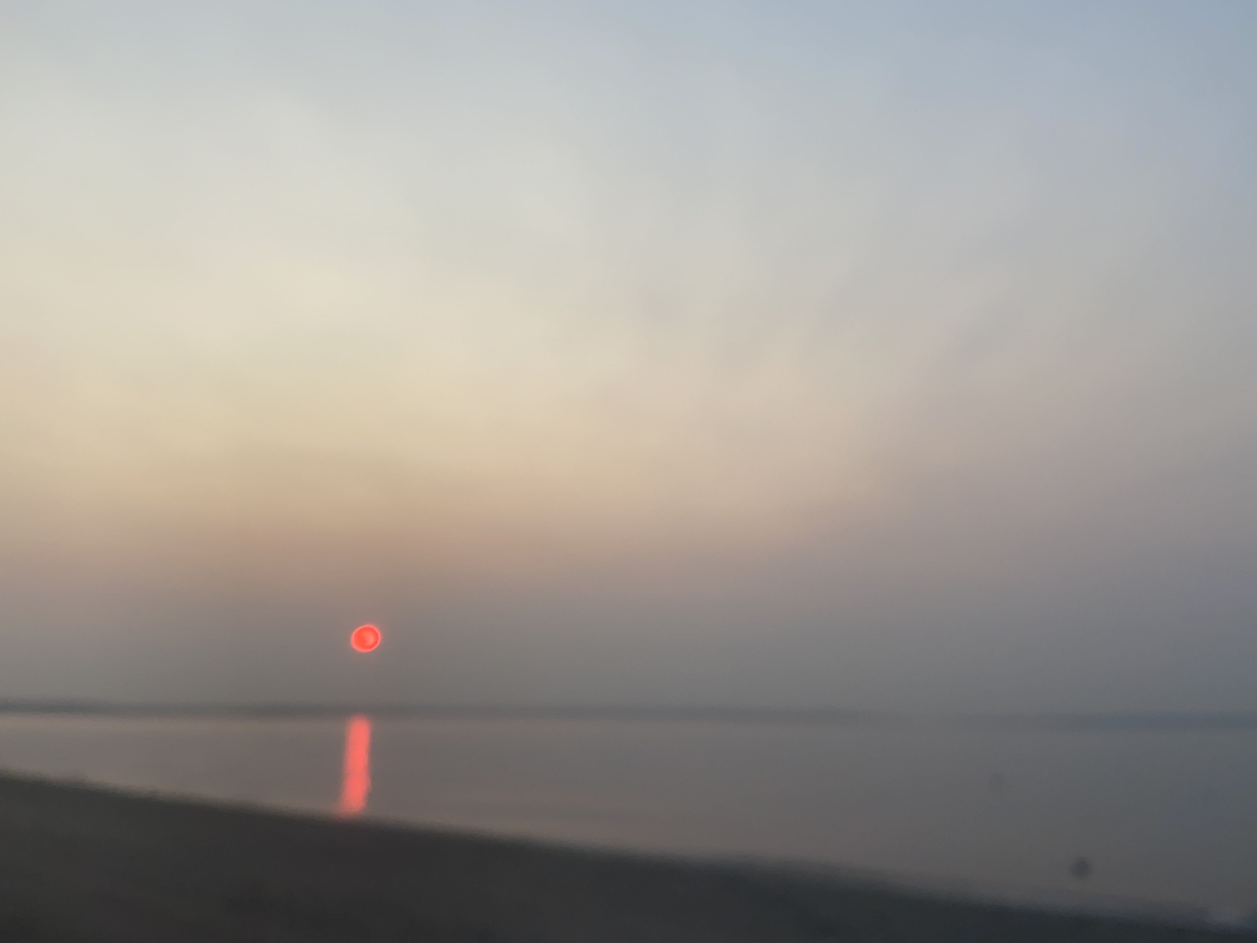 A red sun setting over the ocean.