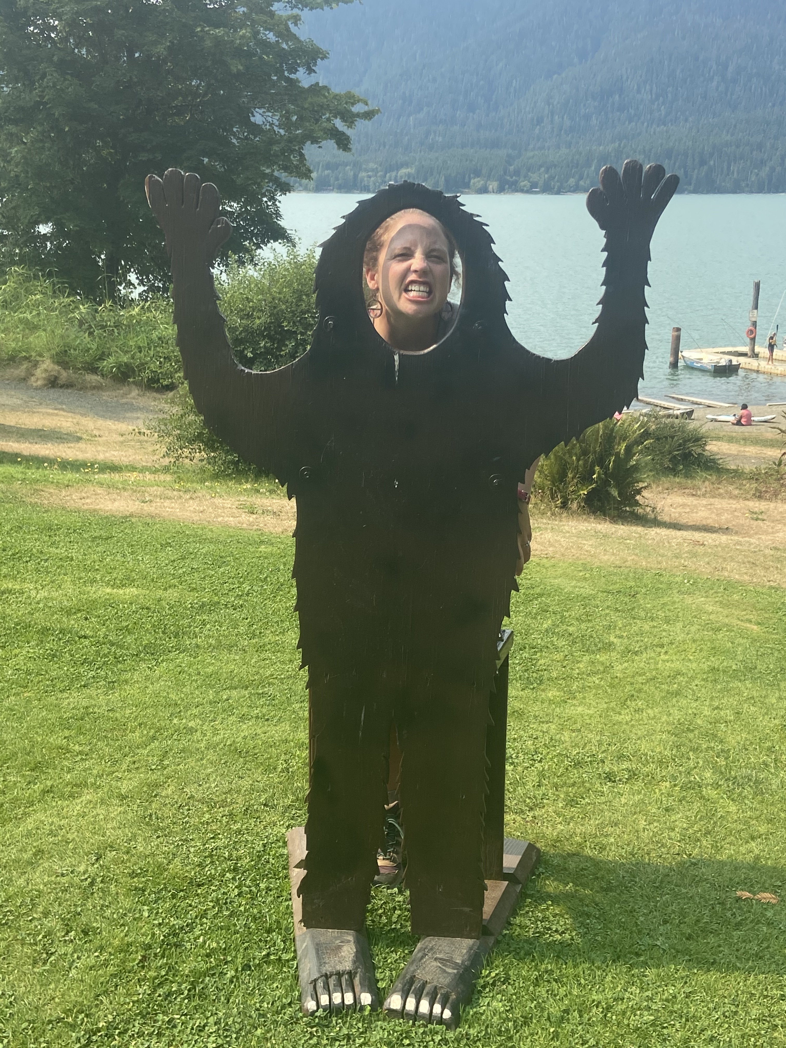 A person behind a cutout of Big Foot, making a grimacing face through the cutout face hole.