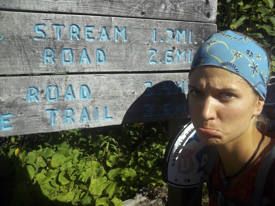 A picture of Anna standing near a sign that says "end of the trail." She's sticking out her bottom lip in sadness at being at the end.