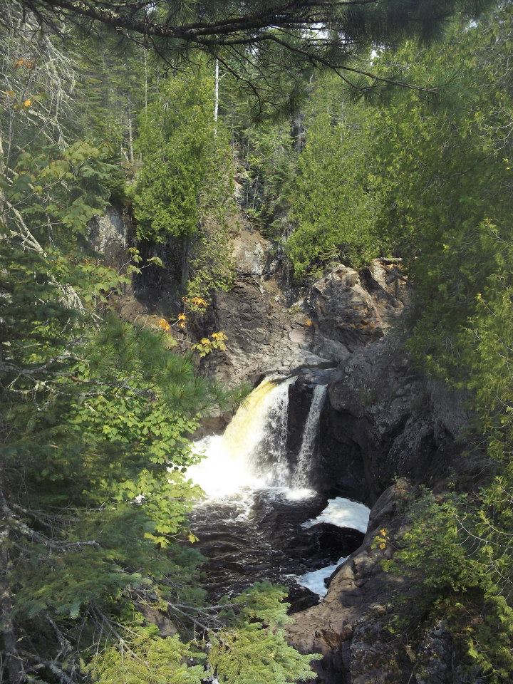 A picture of a waterfall through the trees.