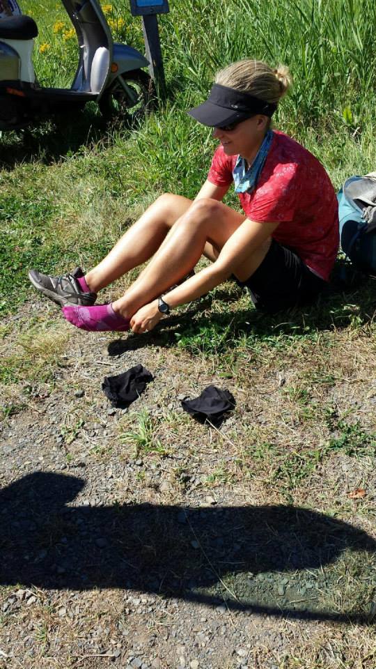 Anna sitting on the ground and putting on socks and shoes to head up to the overlook.