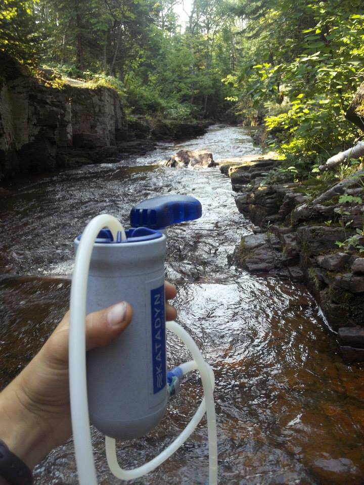 A picture of a water filter with a clear stream behind it.