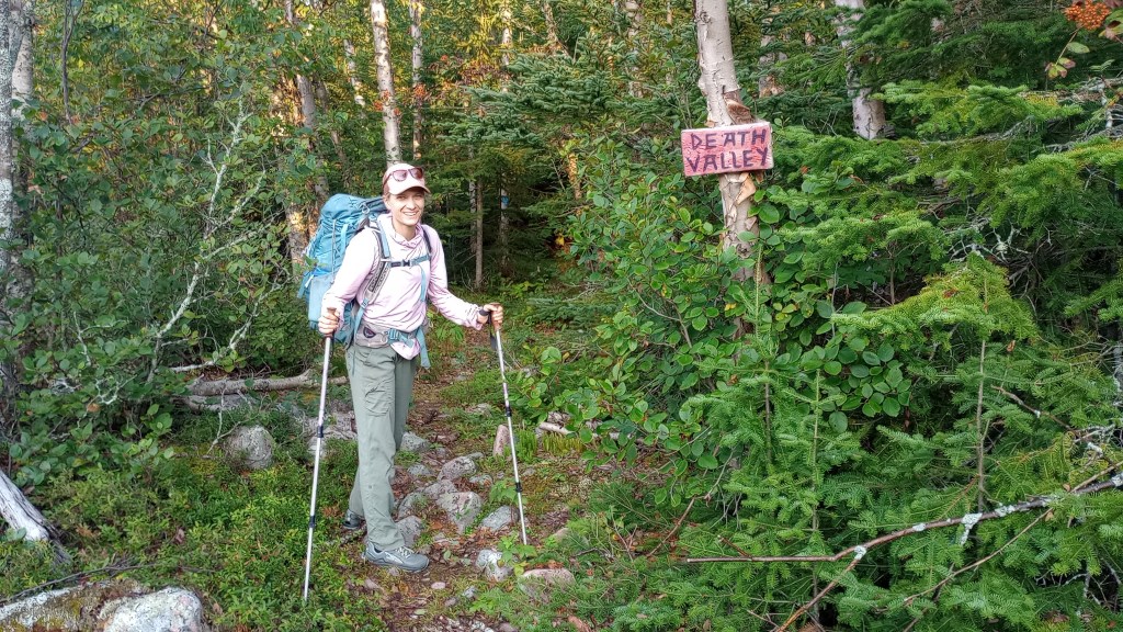A hiker about to head down a trail. A hand painted sign says "Death Valley".