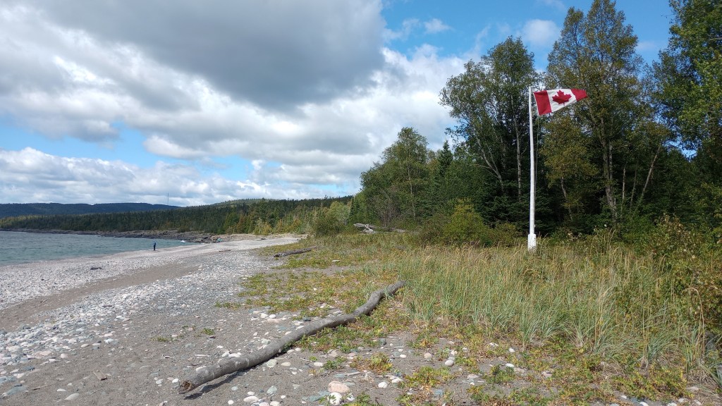 A Canadian flag flying next to the Lake Superior beach.