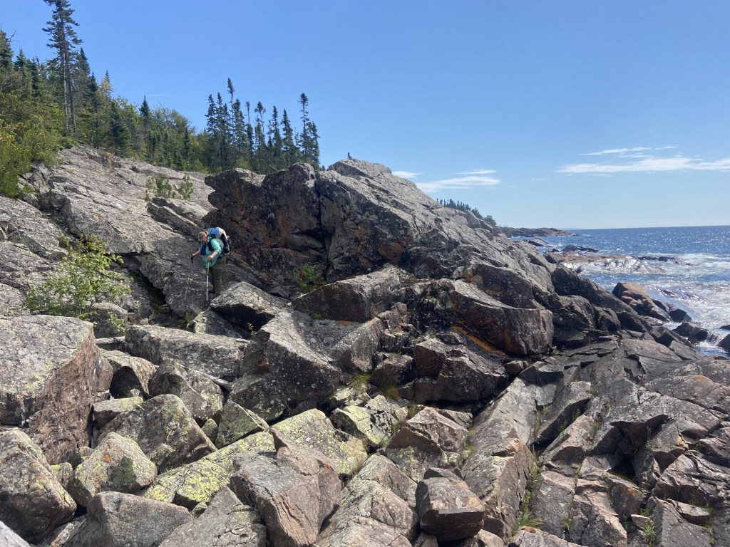 A woman with a backpack traversing a field of rock.