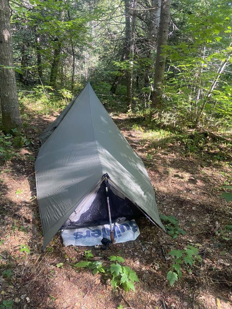 A small tent at a wooded campsite.